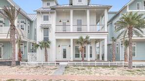 A beachfront property with a two-story building, a balcony, and palm trees.