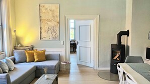 A living room with a grey sofa, a coffee table, a fireplace, and a door leading to another room. - Erholung mit Hof-idylle & Kamin im Einmaligen Denkmal von 1477, 120qm, Parkpl (Quedlinburg)