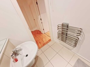 A bathroom with a white sink, a mirror, and a towel rack. - Deluxe 2-bed Apartment Near Shoreditch (London)