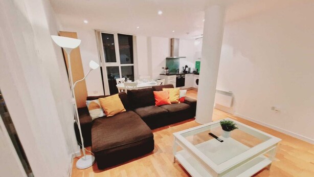 A modern living room with a brown sectional sofa, a glass coffee table, and a white floor lamp.