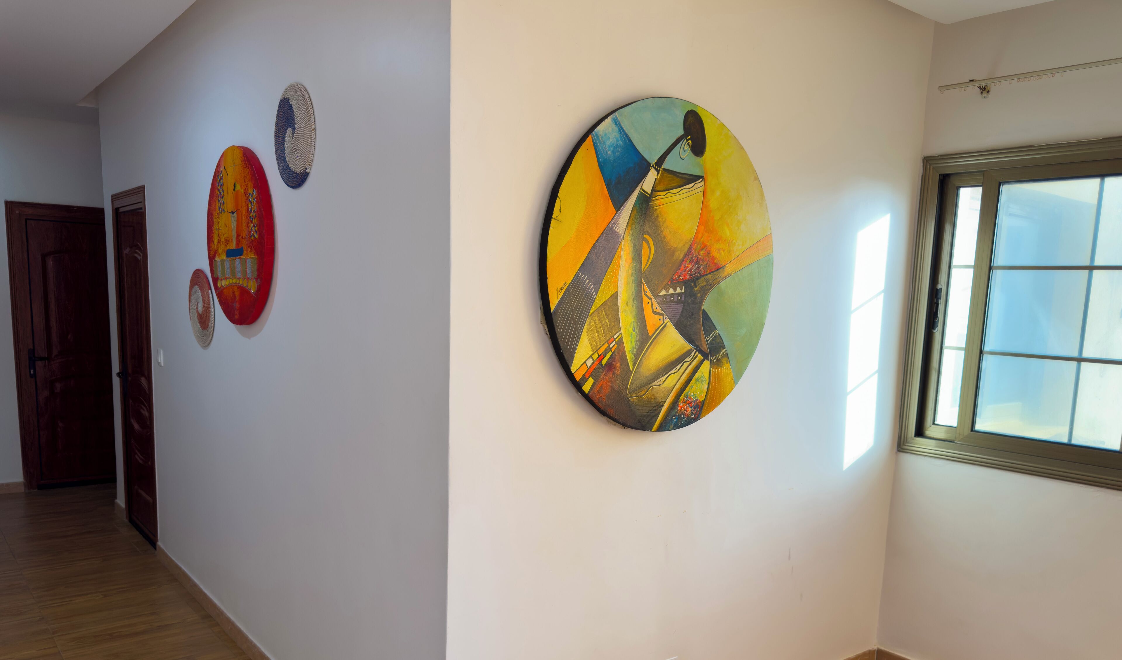 A hallway with three artworks on the wall and a window on the right.