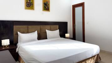 A neatly made bed with white linens, a dark headboard, and two bedside lamps.
