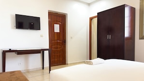 A bedroom with a bed, a desk, a television, and a wardrobe. - Oasis Seaside by Barok (Dakar)