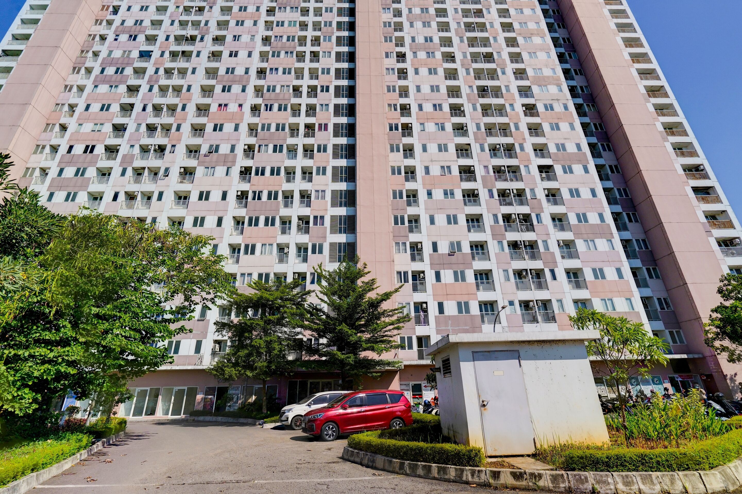 Un immeuble résidentiel de grande hauteur doté de nombreux balcons, d’un espace de stationnement et de quelques espaces verts.