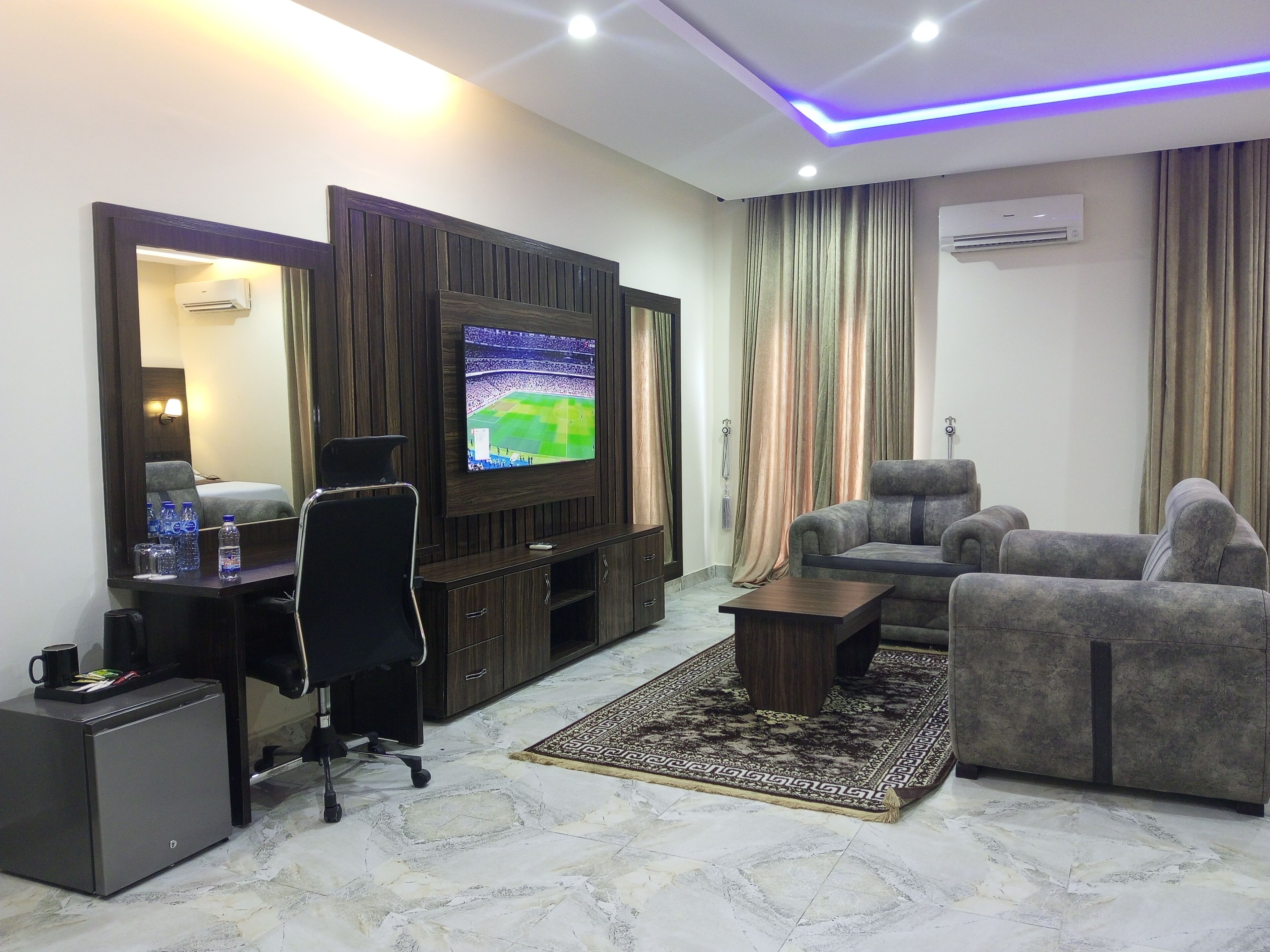 Una sala de estar moderna con una televisión de pantalla plana, un sofá, una mesa de centro y un escritorio con una silla.