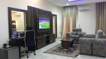 Una sala de estar moderna con una televisión de pantalla plana, un sofá, una mesa de centro y un escritorio con una silla.