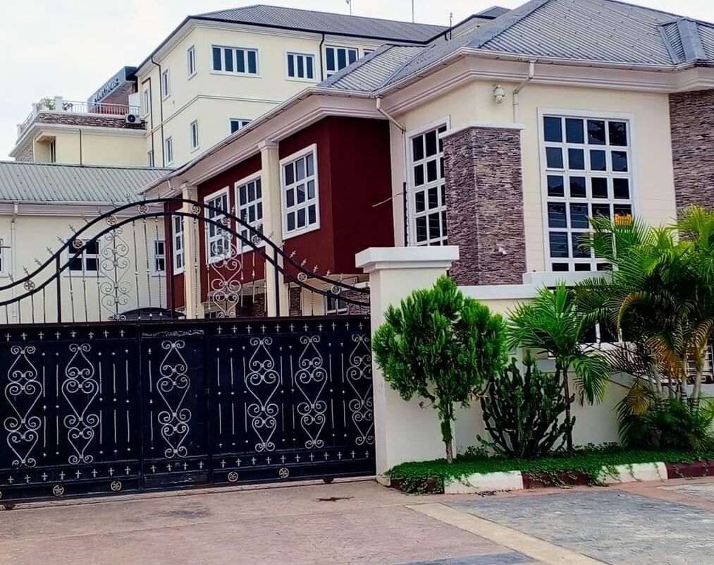 Una casa residencial con entrada protegida por una reja, fachada de piedra y un jardín bien cuidado.