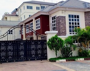 A residential house with a gated entrance, a stone facade, and a well-maintained garden. - Vinpy Hotels (Uyo)