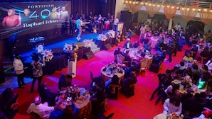 Un evento formal con escenario, público y mesas dispuestas para cenar.