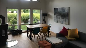 Un espacio habitable amplio con una mesa de comedor, sillas, un sofá y un ventanal con vistas a un jardín.