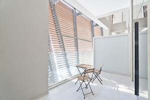 A modern, well-lit room with large windows, a foldable table, and chairs.