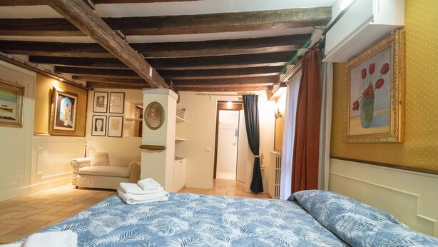 A bedroom with a bed, a sofa, and a bathroom visible through an open door. - Ca' Rielo (Venice)