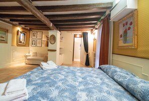A bedroom with a bed, a sofa, and a bathroom visible through an open door. - Ca' Rielo (Venice)