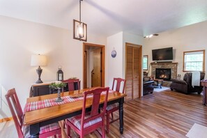 Un coin repas avec une table et des chaises en bois, une lampe et une cheminée en arrière-plan.