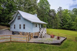 Une maison bleu clair avec des fondations en pierre, une terrasse en bois et un escalier menant à un porche.