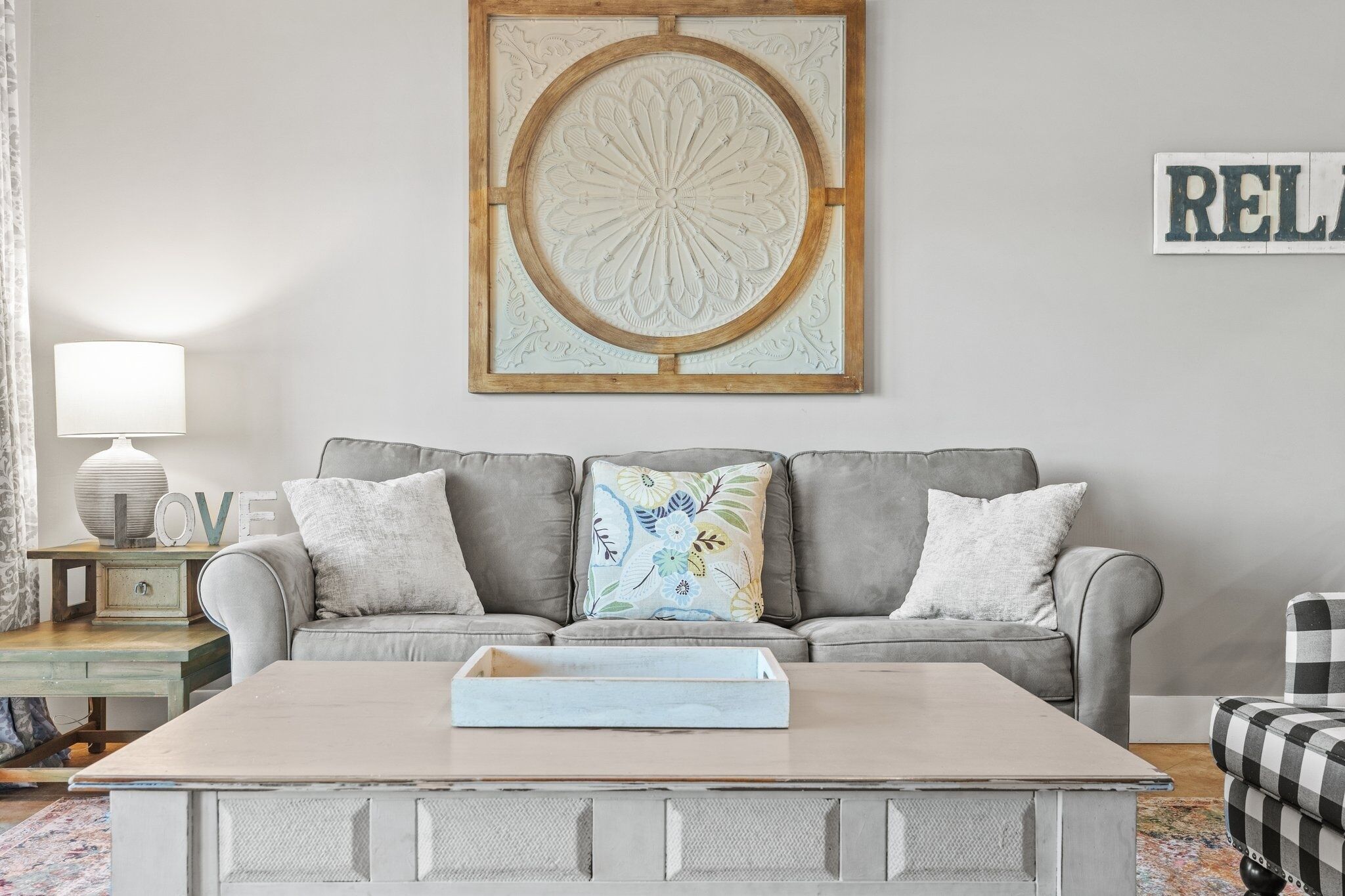 A living room with a grey sofa, a wooden coffee table, and a decorative wall piece.