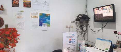 A reception desk with informational posters, a clock, and a television screen.