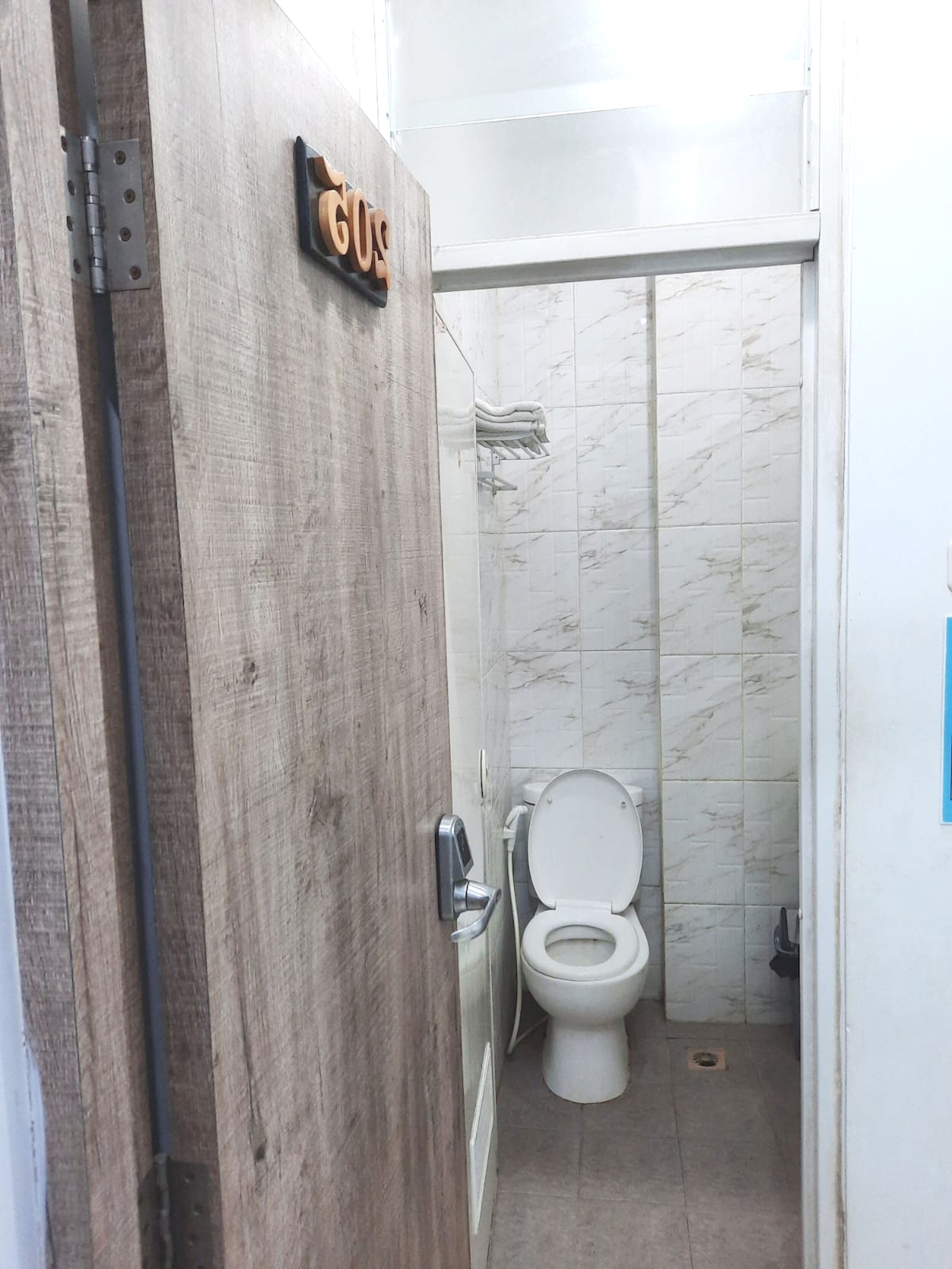 Une salle de bain avec une porte en bois, des toilettes et un espace douche.
