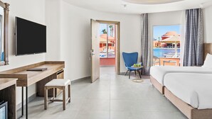 Une chambre d’hôtel comprenant un lit, un bureau avec une chaise, une télévision et une vue sur une piscine et un bâtiment situés à l’extérieur.