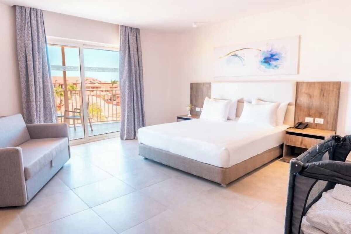 Une chambre d’hôtel avec un lit, un canapé, un bureau et une vue sur l’extérieur.