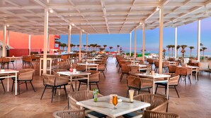 Un espace de restauration en plein air avec plusieurs tables et chaises, un bar et une vue sur la plage.