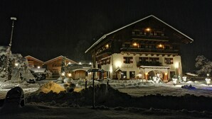 A large, multi-story building with a traditional Alpine architectural style, featuring a prominent entrance and multiple windows.