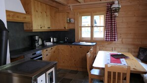 A kitchen with wooden cabinets, a stove, a sink, and a dining area with a table and chairs.