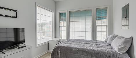 A bedroom with a bed, a TV on a dresser, and a ceiling fan.