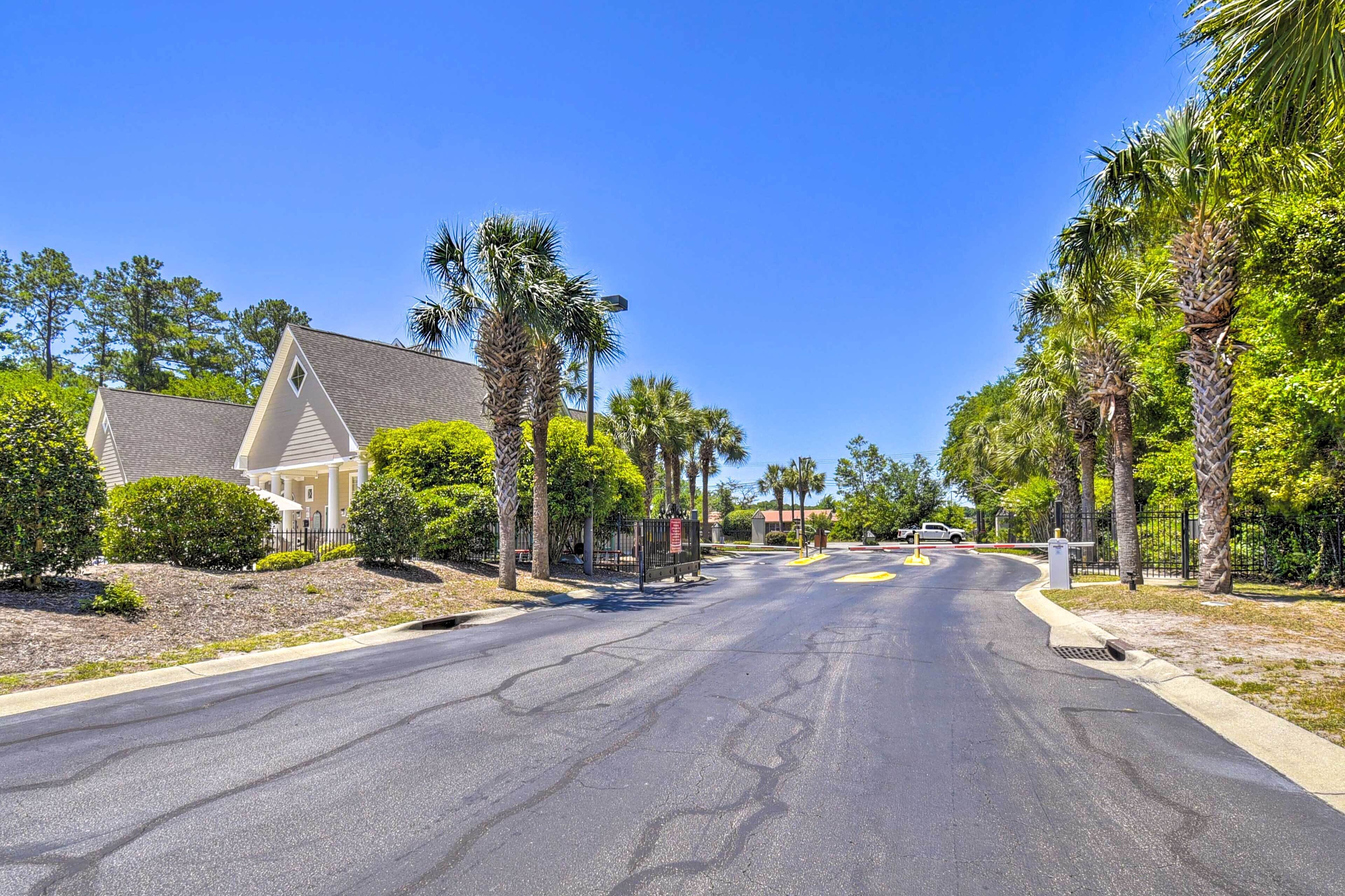 A residential street with houses, palm trees, and a clear blue sky.