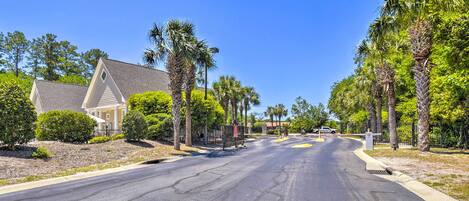 A residential street with houses, palm trees, and a clear blue sky.