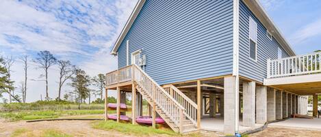 A two-story building with a blue exterior, a wooden deck, and a covered outdoor area.
