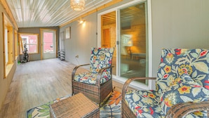 A room with wicker furniture, a ceiling fan, and a large sliding glass door leading to an outdoor area. - Oscoda Cabin w/ Charcoal Grill: Walk to Lake Huron (Oscoda)