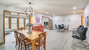 A spacious dining area with a wooden table and chairs, a chandelier, and a view of the outdoors through large windows. - 'stay and Play' - Hot Springs Village Home! (Hot Springs Village)