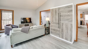 A modern living room with a sofa, a television, a side table, and a large wardrobe. - 'stay and Play' - Hot Springs Village Home! (Hot Springs Village)