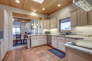 A kitchen with white cabinets, a microwave, and a dishwasher. There is a dining area with chairs and a table. - Serene Santa Fe Getaway w/ Hot Tub & Fireplace! (Santa Fe)