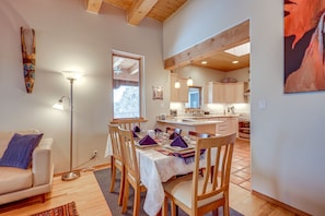 A dining area with a table set for four, wooden chairs, a floor lamp, and a view into the kitchen. - Serene Santa Fe Getaway w/ Hot Tub & Fireplace! (Santa Fe)