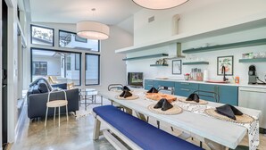 Una cucina moderna con zona pranzo, che presenta un tavolo grande con sottopiatti intrecciati e panche, un forno a incasso e una macchina da caffè.