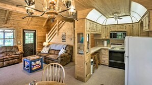 A cozy log cabin interior with a living room, dining area, kitchen, and a staircase. - Waterfront Lake Leelanau Log Cabin w/ Private Dock (Lake Leelanau)