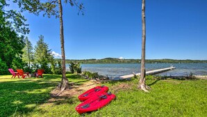 A lakeside setting with kayaks, red chairs, and a dock. - Waterfront Lake Leelanau Log Cabin w/ Private Dock (Lake Leelanau)