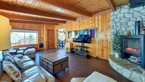 Ein gemütliches Wohnzimmer mit Kamin aus Stein, Holzwänden und einem an der Wand befestigten Fernseher.