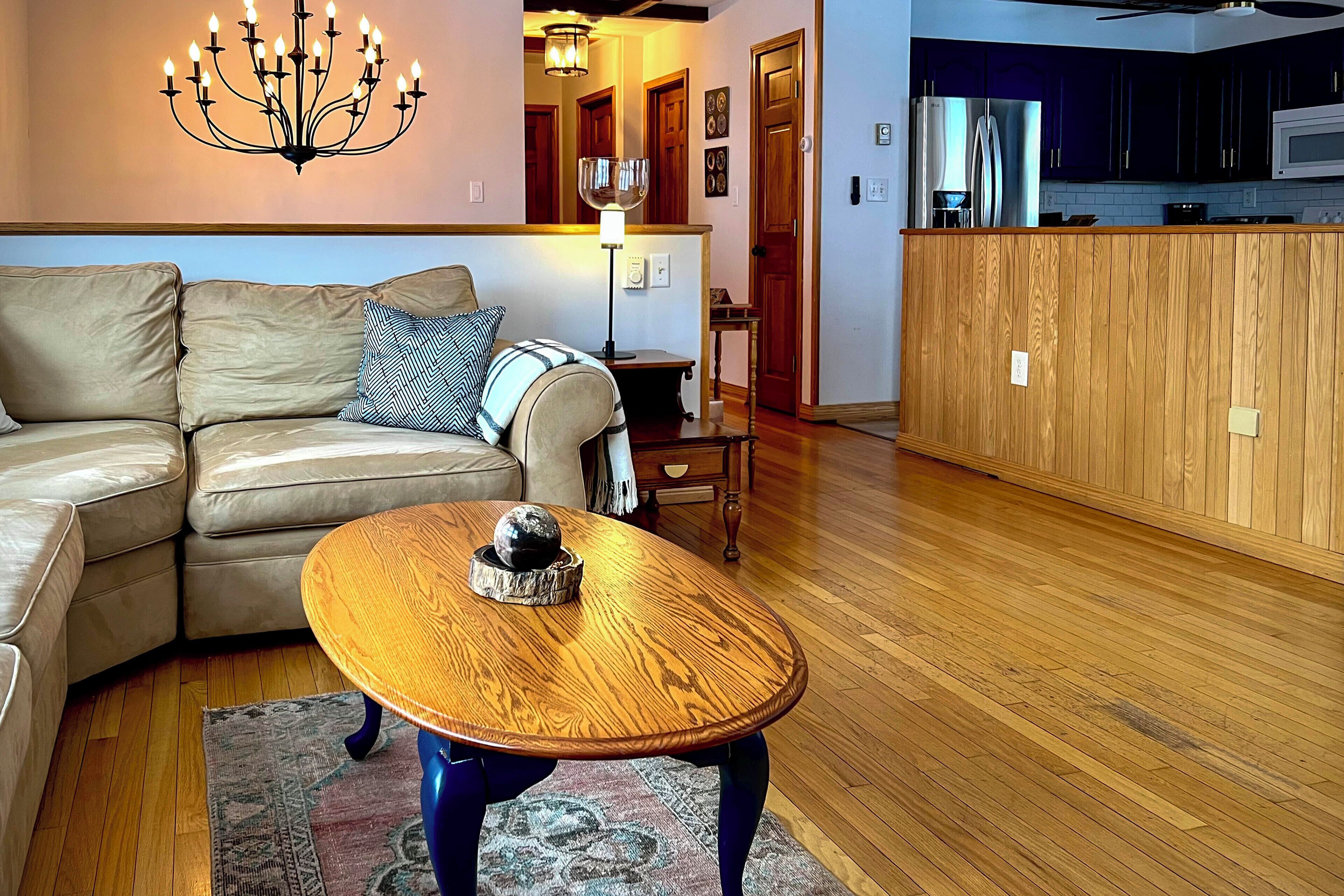 Una sala de estar con una mesa de centro de madera, un sofá color crema y un candelabro.