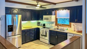 A modern kitchen with dark blue cabinets, stainless steel appliances, and a wooden ceiling fan. - Vacation Rental Home ~ 2 Mi to Windham Mountain! (Windham)