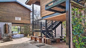 A rustic lodge with a wooden exterior, outdoor seating area, and a staircase leading to an upper level. - Guadalupe Riverfront Studio w/ Private Balcony (Seguin)
