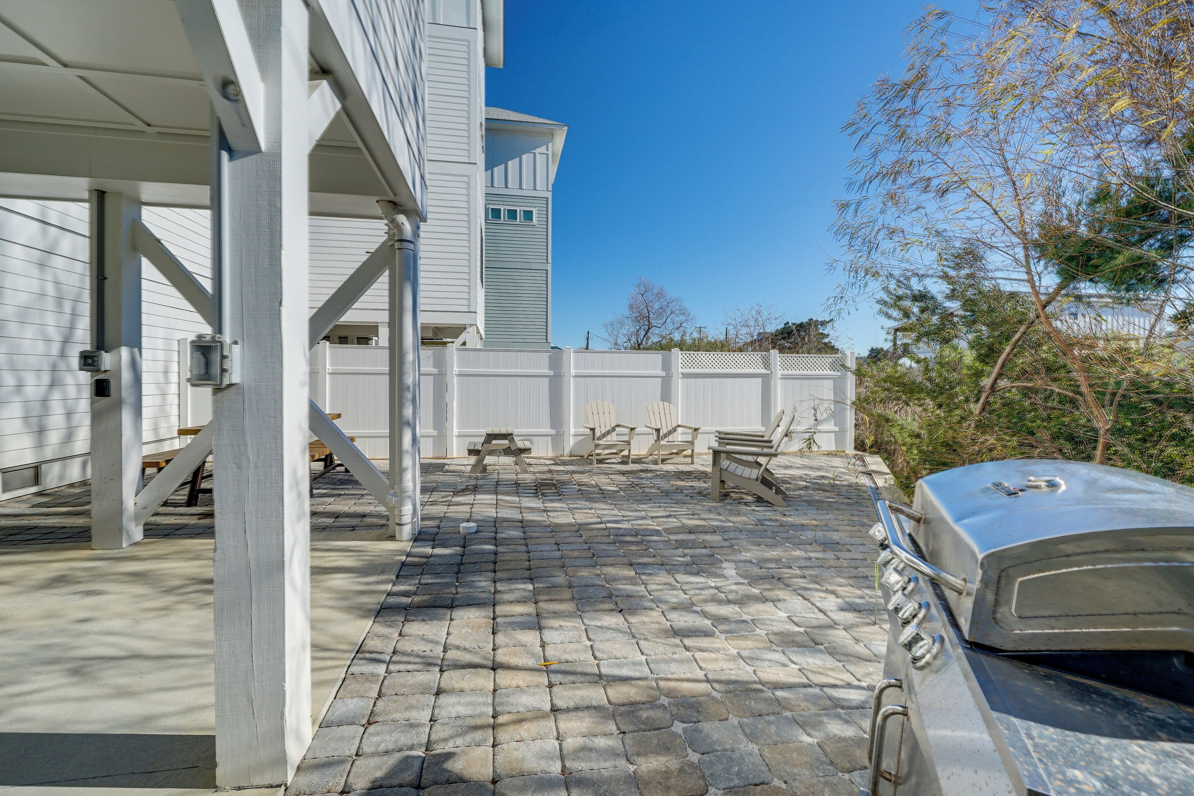 A covered patio with a grill, outdoor seating, and a stone-tiled floor.
