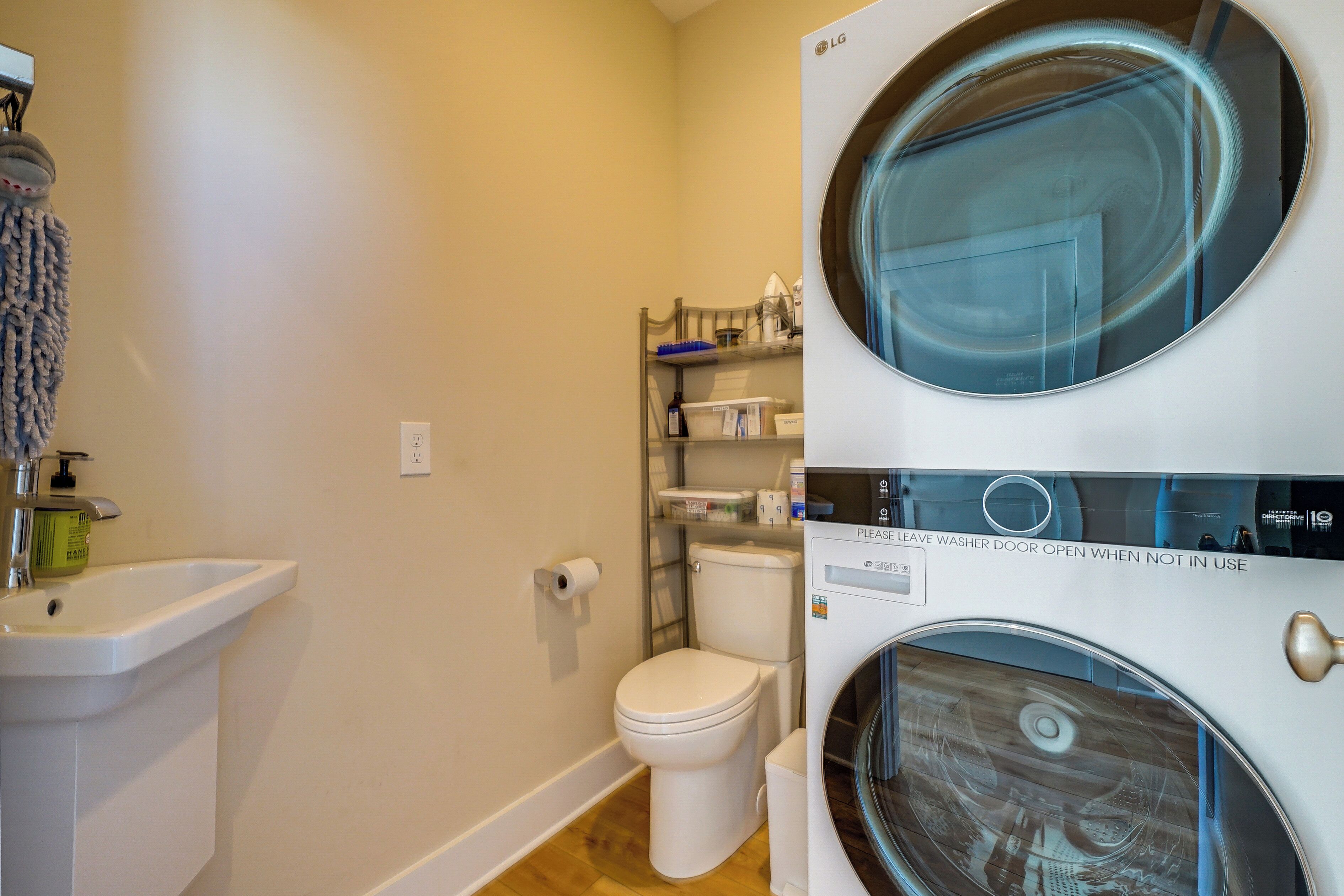 A compact bathroom with a sink, toilet, and stacked washer-dryer unit.