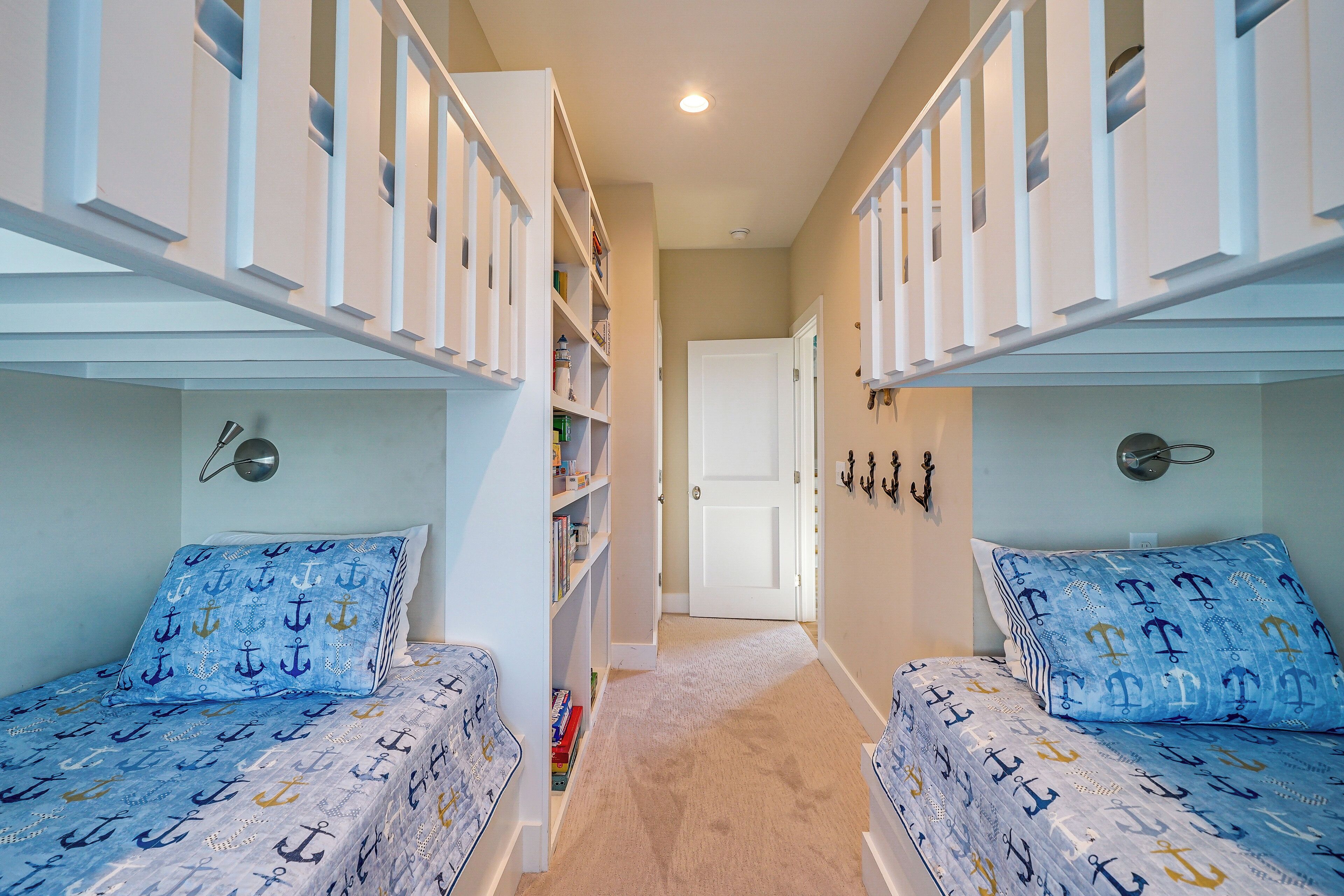 A room with bunk beds, a bookshelf, and a door leading to another room.