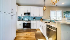 Une cuisine moderne avec des armoires blanches, des appareils en acier inoxydable et un plancher en bois.