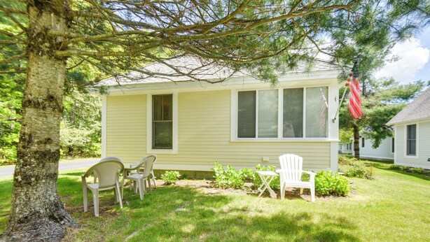 A single-story house with a front porch, two chairs, and a small garden area. - Sunny Wells Cottage - 1 Mi to Moody Beach! (Wells)