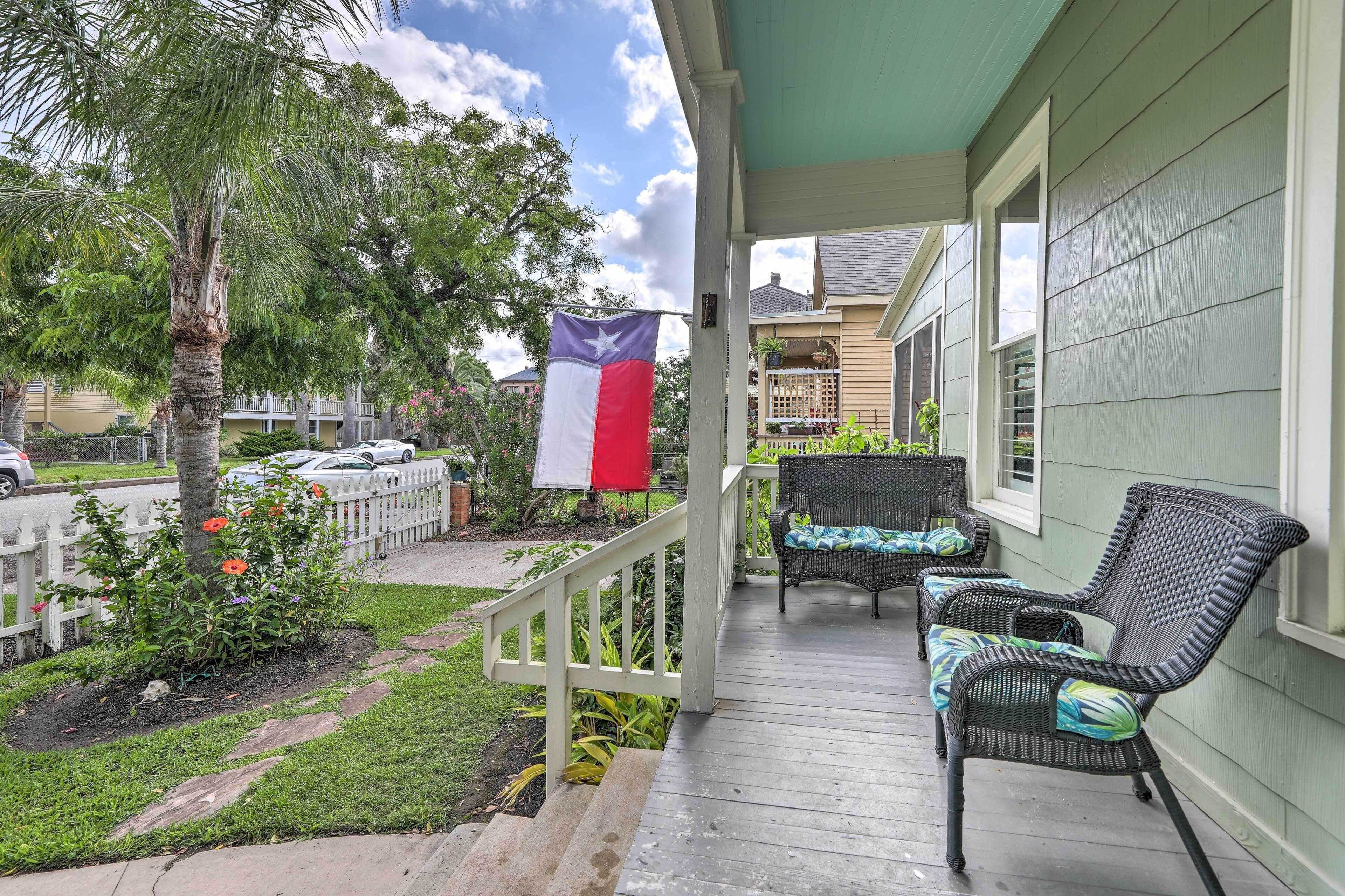 Een veranda met rieten stoelen en een Texas vlag.