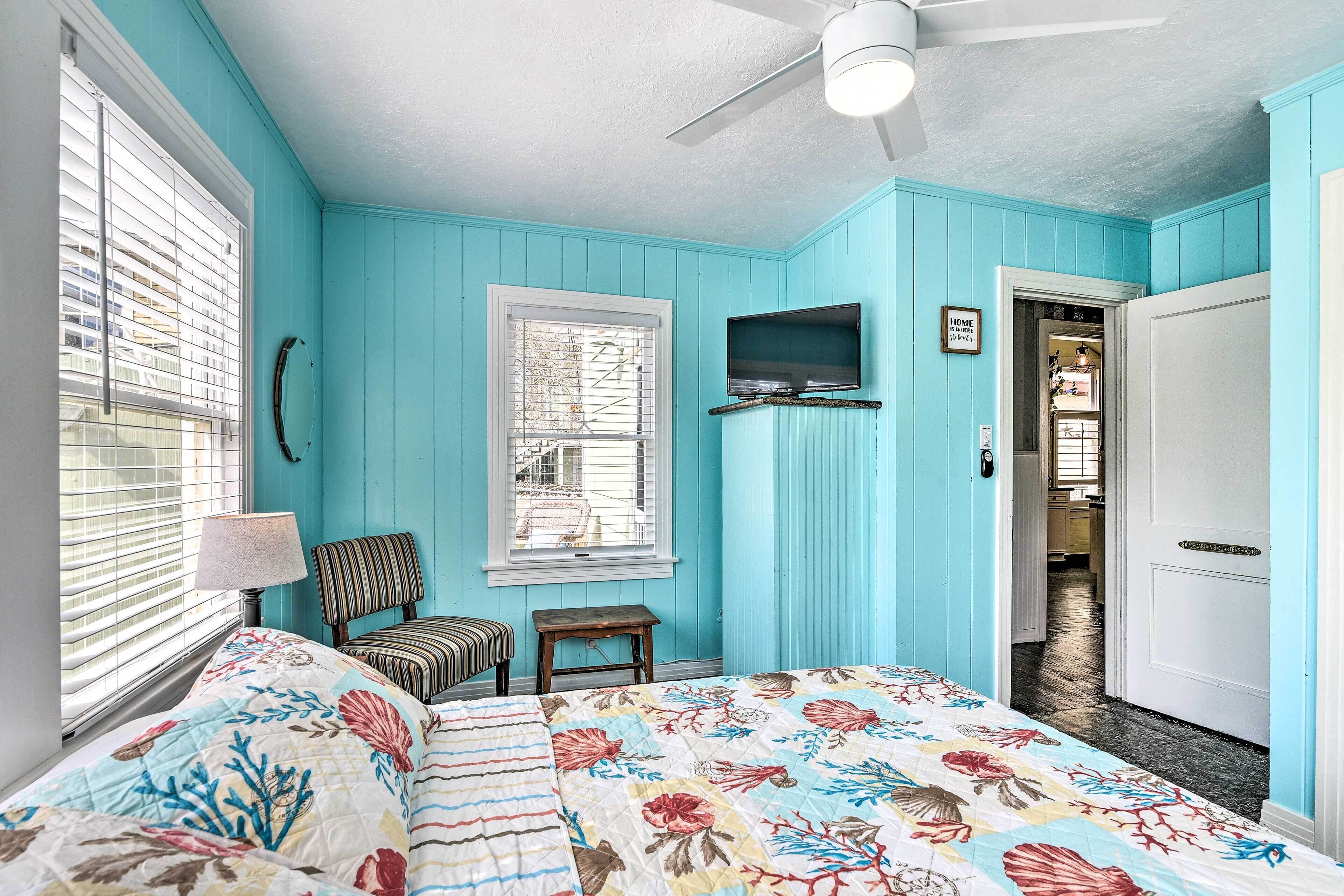 A room with a bed, a chair, a television, a window, and a door.